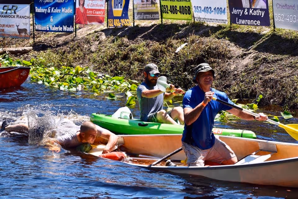 A man jumping into the back of a sinking canoe while his partner paddles.