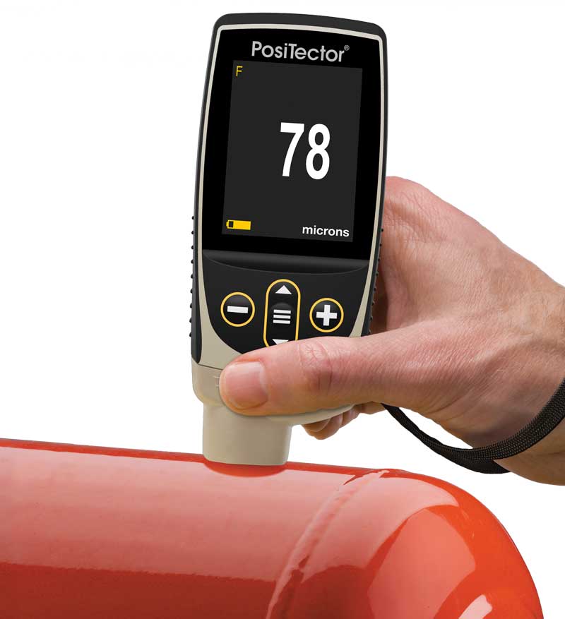 Photo of the PosiTector 6000 measuring paint thickness on a red tank