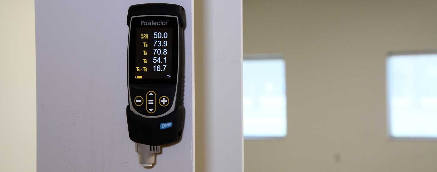 Foto do PosiTector DPM fazendo leituras do air ambiente acima de um local de teste ASTM F2659