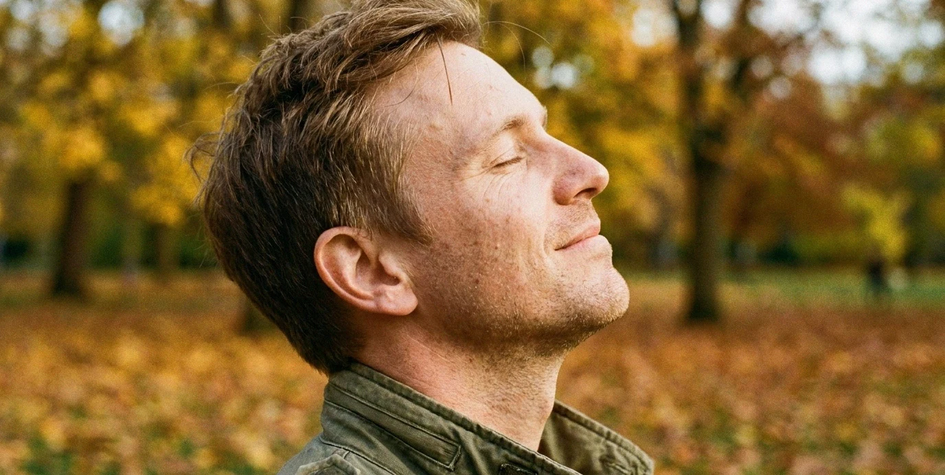 Ein Mann genießt das freie Atmen und sein harmonisches Profil im Freien nach einer Nasenkorrektur.