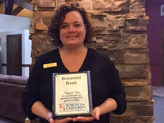 Judy London of Rensant bank holding a thank you plaque from Voice for Children