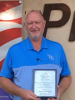 Tom Ready of Wood's Printing holding a recognition plaque for our sponsors