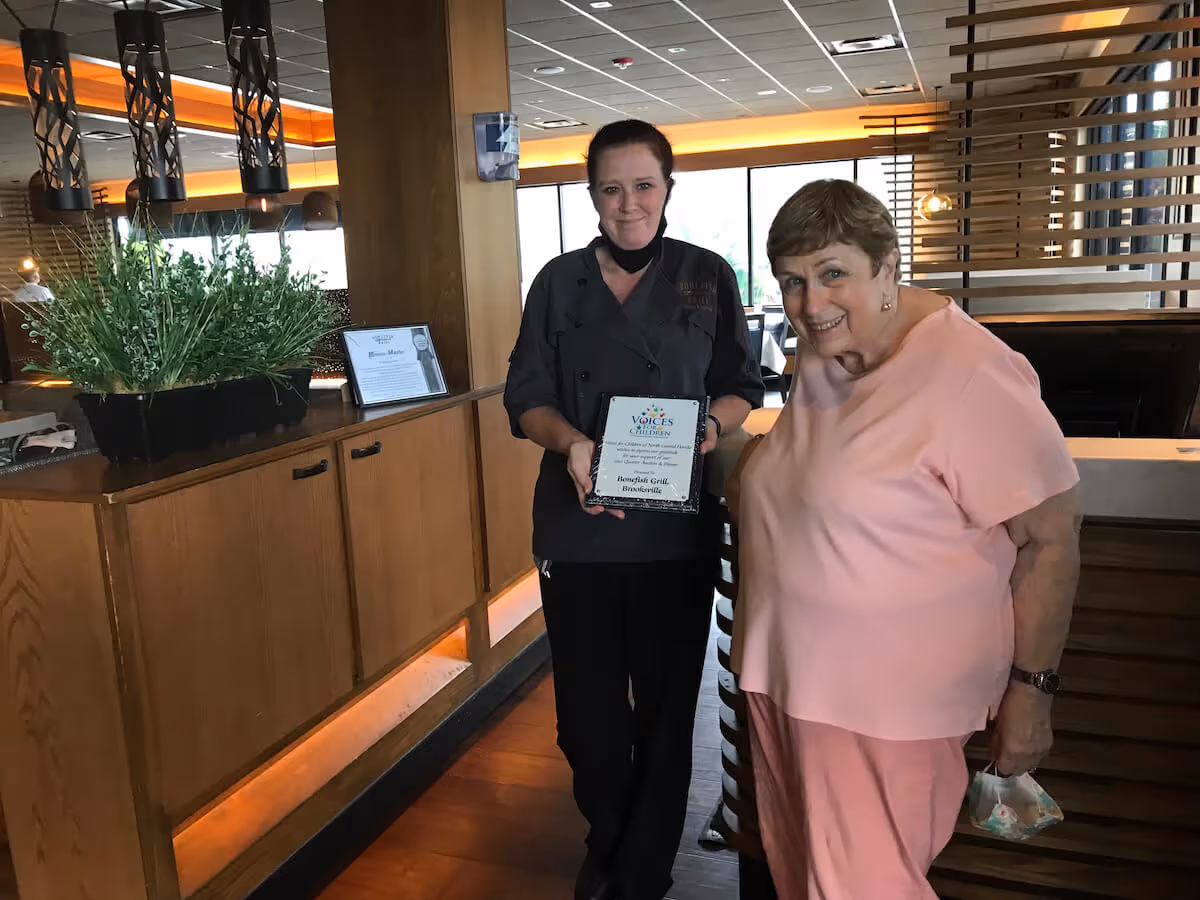Nicki Lawter receiving a recognition plaque from Voices For Children's Peg Donovan