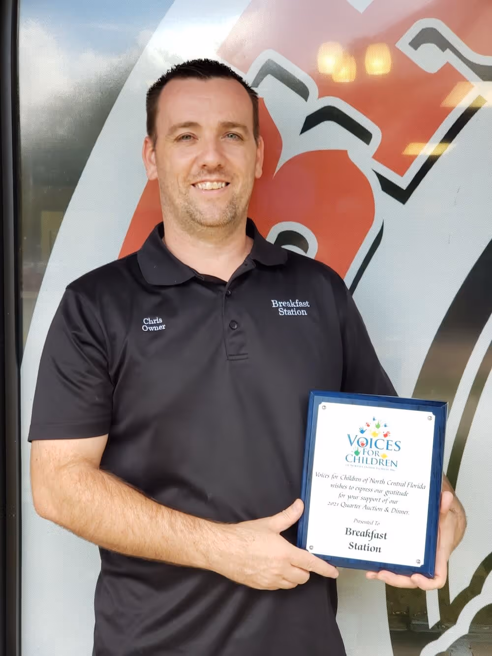 Chris Morra holding an appreciation plaque for the Breakfast Station in Beverly Hills