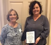 Sue Carpenter presenting Judi London of Renasant Bank with a thank you plaque from Voices for Children