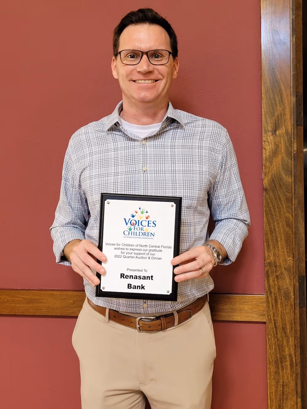Adam Lombard of Renasant Bank in Ocala holding a Voices for Children Thank You plaque