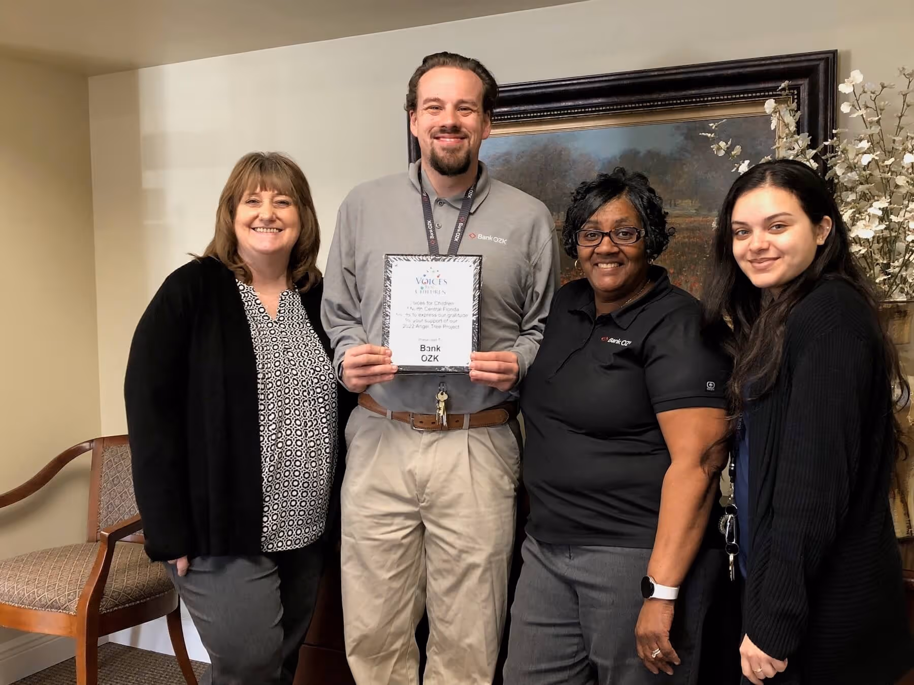 Bank OZK representatives holding an appreciation plaque from Voices for Children