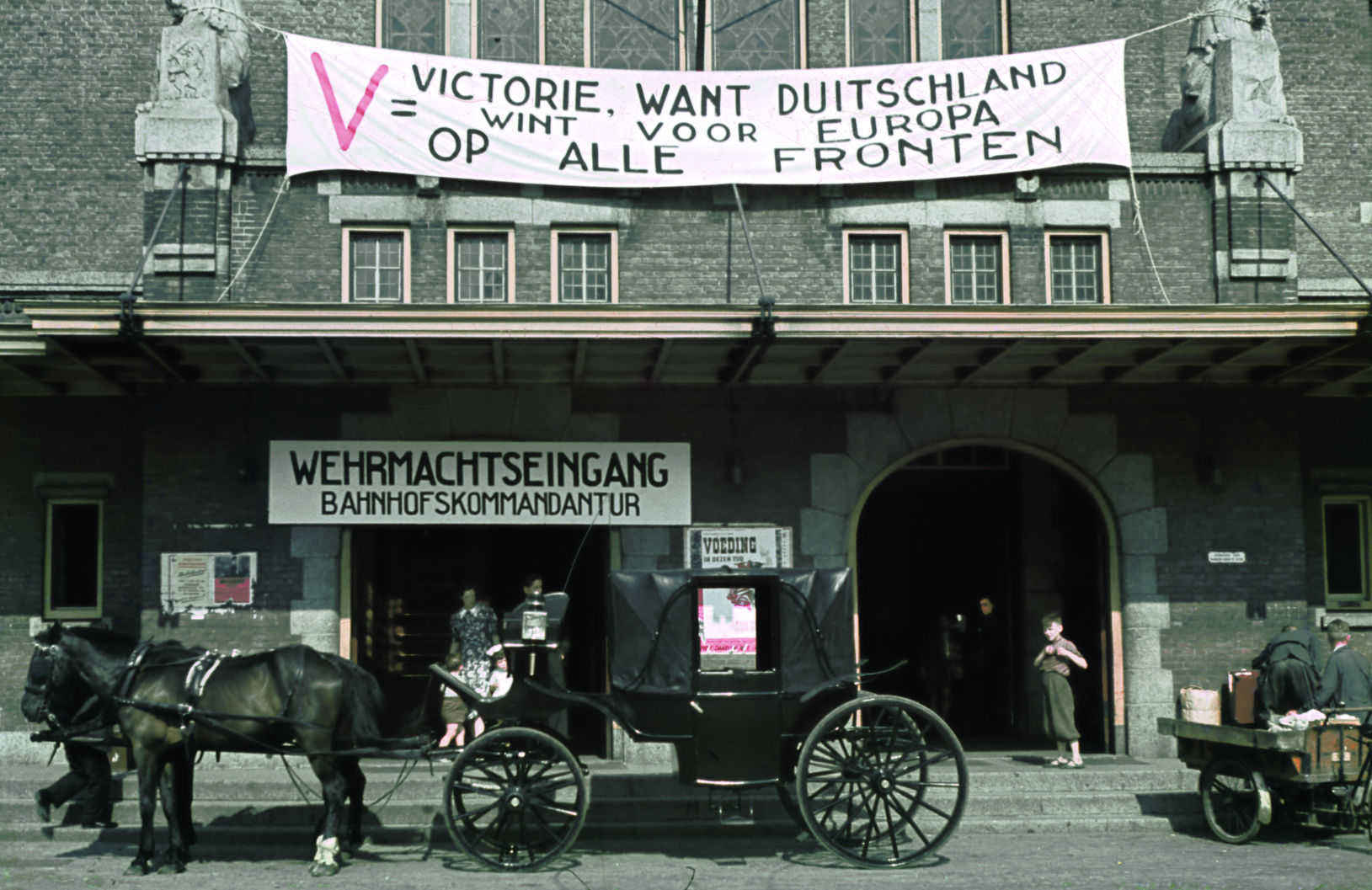 ‍foto: Alphons Hustinx | Maastricht 194, koets met paarden voor station met spandoeken van de nazi';s