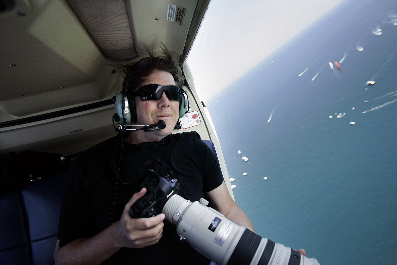 Jasper Juinen met camera en lange lens in de lucht bij open deur vliegtuig