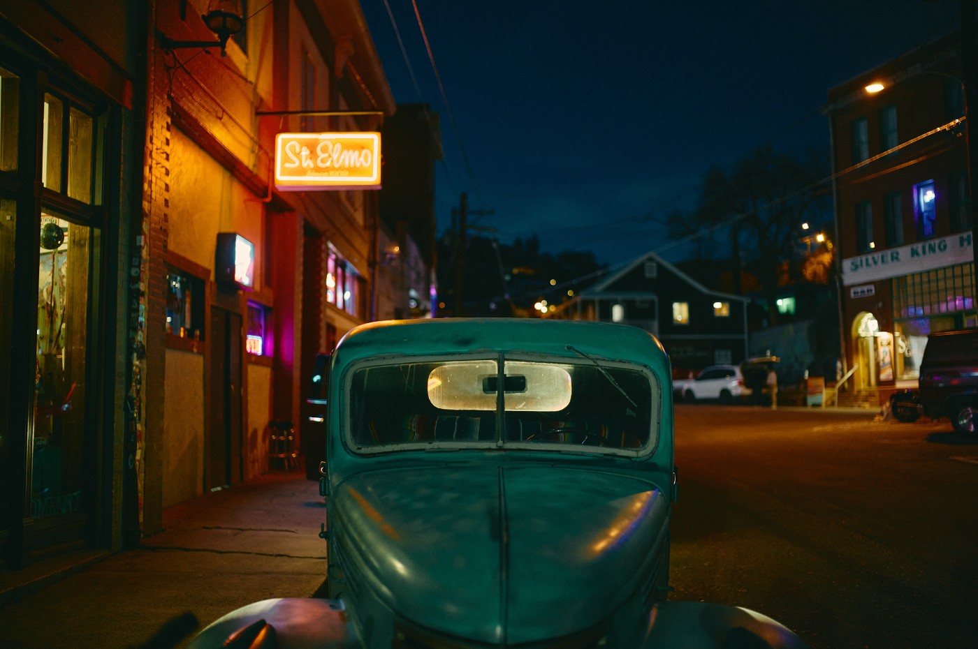 Vintage auto geparkeerd in een straat met neonverlichting bij avond, gefotografeerd met Leica Noctilux-M 35 mm f/1.2 ASPH.