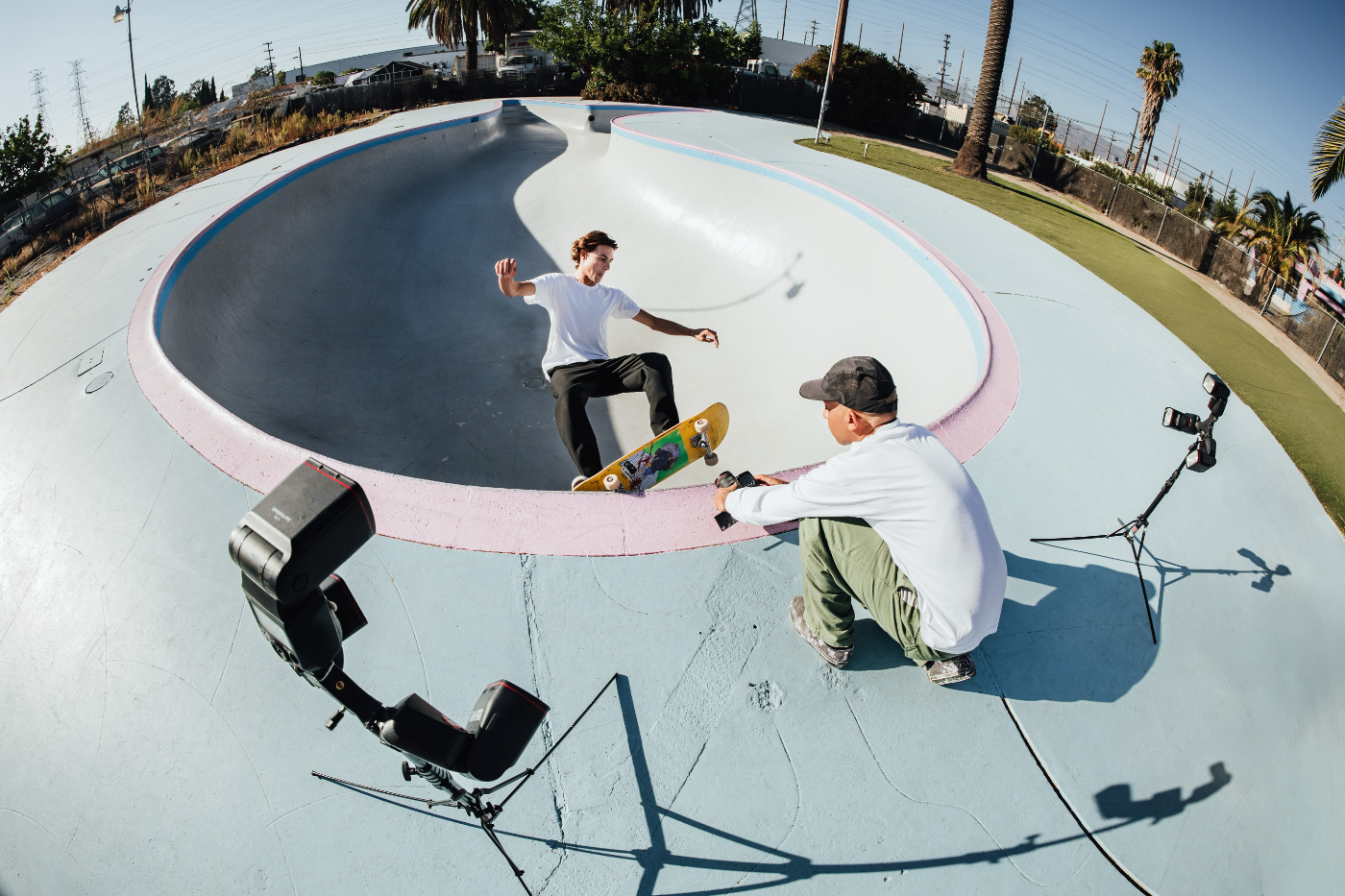 Fotograaf maakt een low-angle actiefoto van een skateboarder in een skatebowl met ultragroothoek fisheye-perspectief en off-camera flitsers.