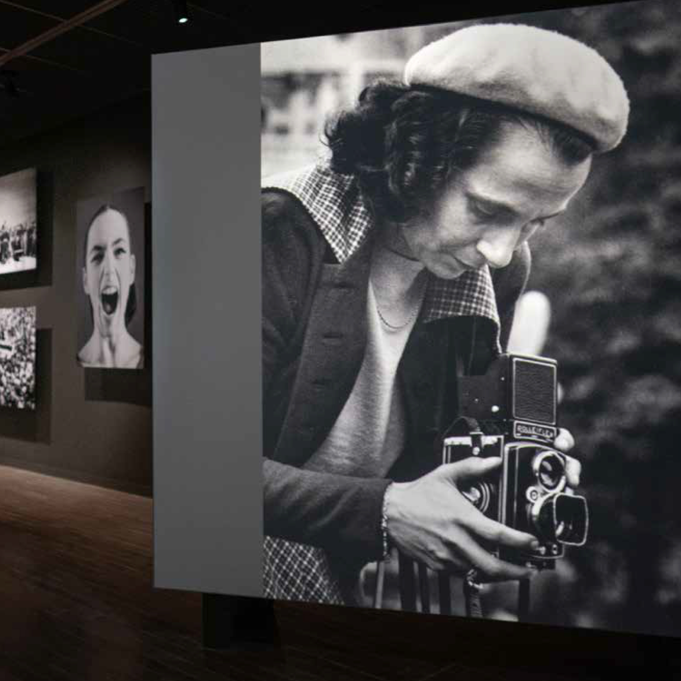 Grote zwart-witfoto van fotograaf Maria Austria met camera in de tentoonstelling Maria Austria was hier
