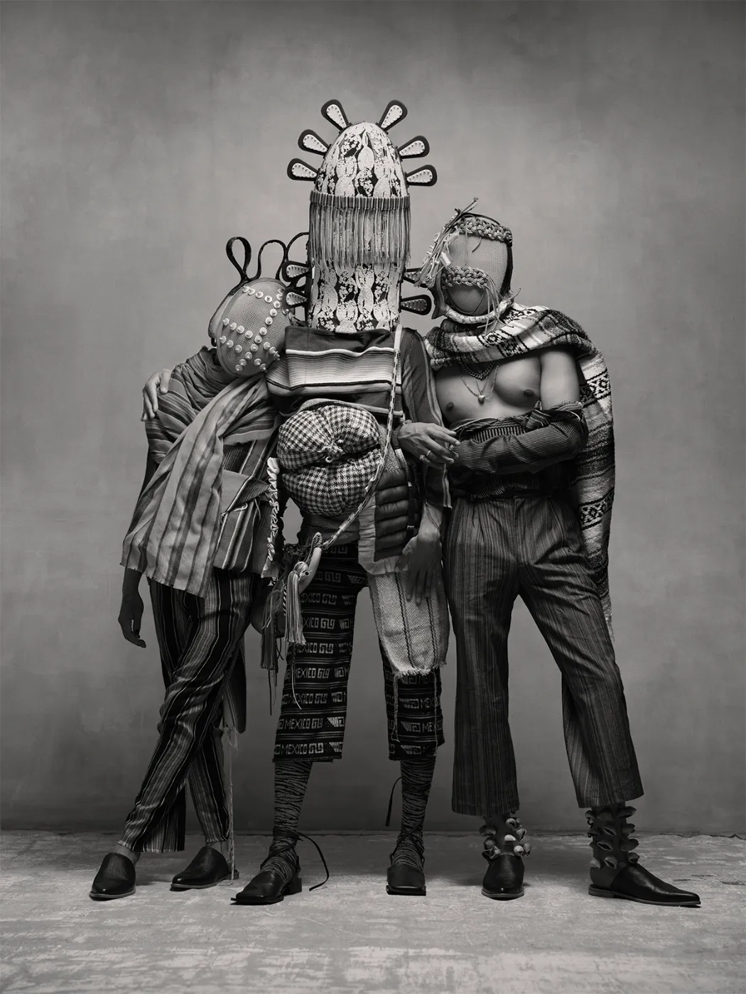Zwart-wit groepsportret van drie personen in experimentele kostuums en maskers, geïnspireerd op Mexicaanse tradities en performancekunst, uit de serie Birds of Mexico City van Pieter Henket.