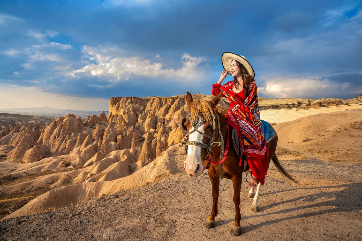 Vrouw te paard in een rotsachtig landschap tijdens golden hour, een populaire setting voor reisfotografie en avontuurlijke portretten.