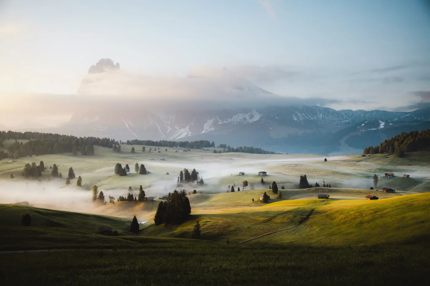 Weids berglandschap met laaghangende mist, groene heuvels en zacht ochtendlicht.