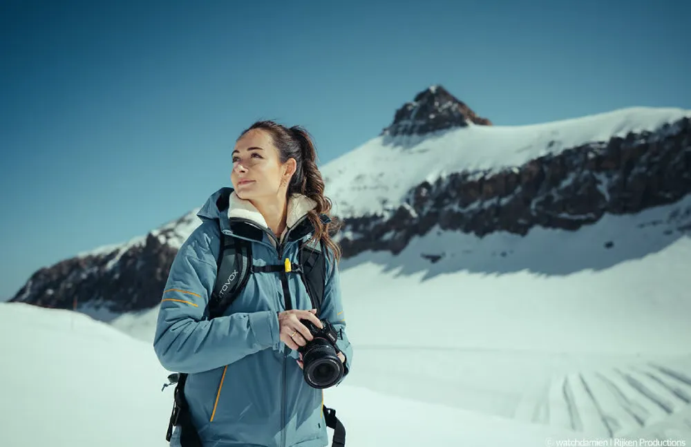 Fotograaf met camera en Samyang AF 14-24mm F2.8 voor L-Mount in een besneeuwd berglandschap.