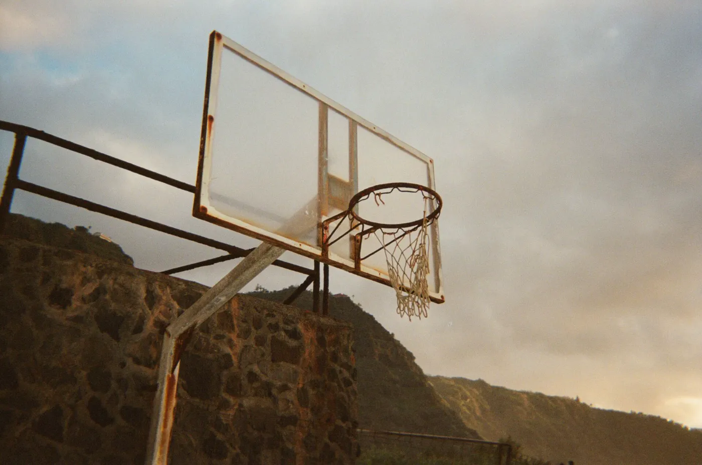 Basketbalring met net tegen een rotsachtige achtergrond, gefotografeerd met analoge uitstraling