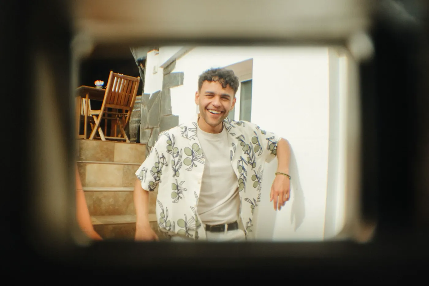 Lachende jongen gefotografeerd door de zoeker van een analoge camera