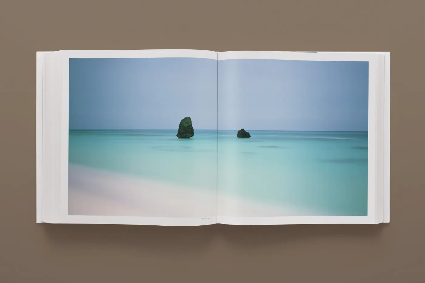 Open boek met een minimalistisch zeelandschap met twee rotsen in stil water uit Fullmoon