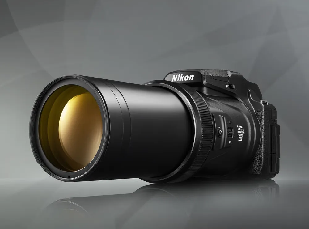 Nikon Coolpix P1100 schuin van opzij met lange zoomlens op grijze achtergrond
