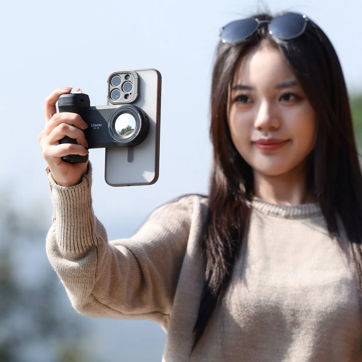 Vrouw houdt een smartphone met magnetische cameragrip omhoog