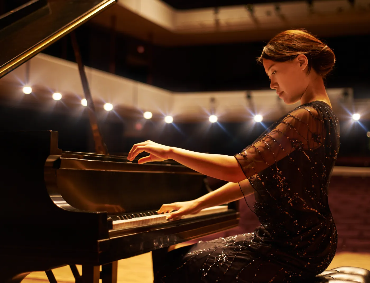 Pianist speelt op een vleugel in een donkere concertzaal