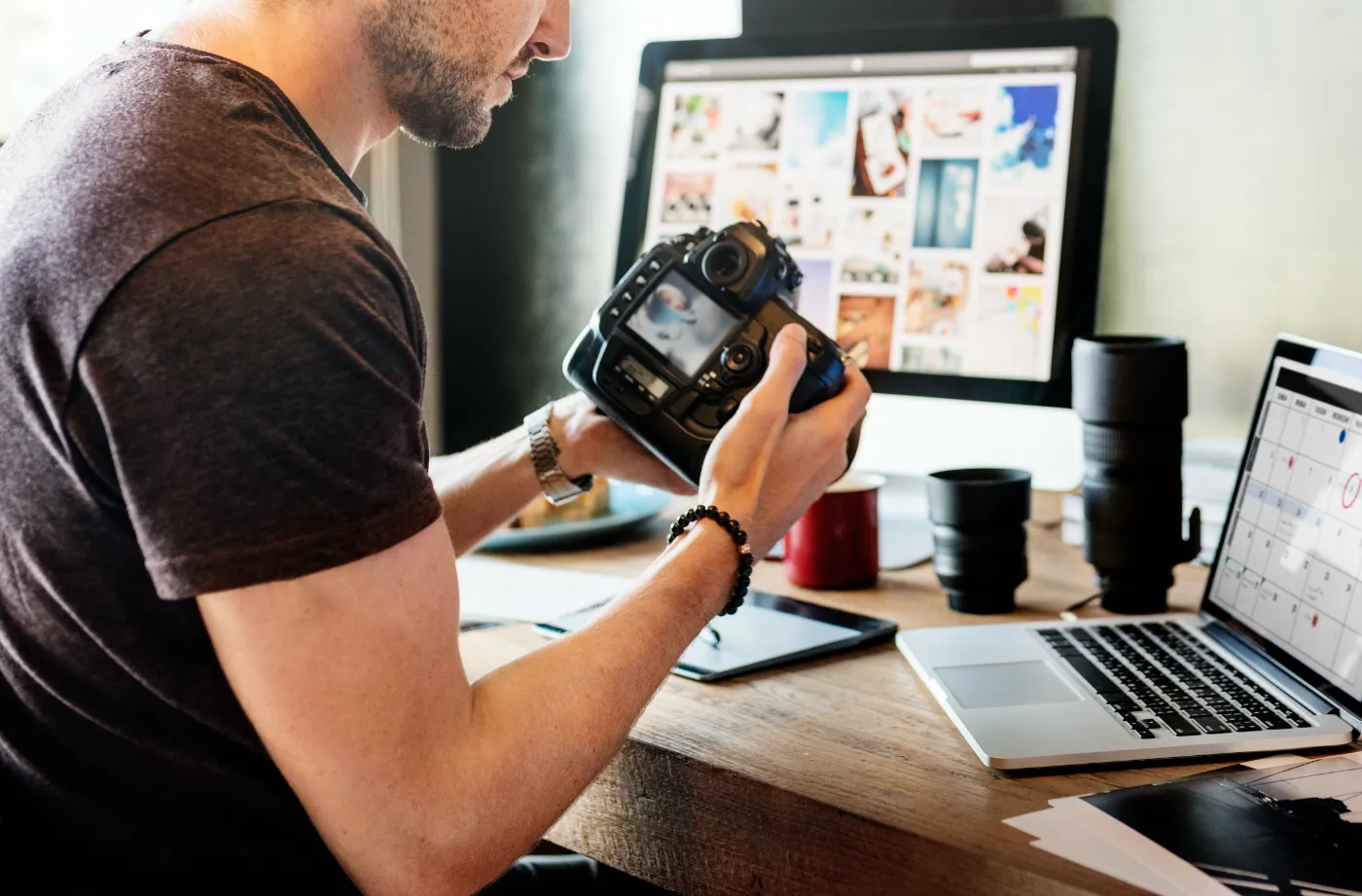 Fotograaf bekijkt zijn camera aan een bureau met fotogalerij op het computerscherm