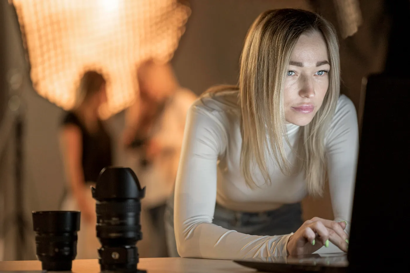Fotograaf werkt aan een laptop met cameralenzen op tafel