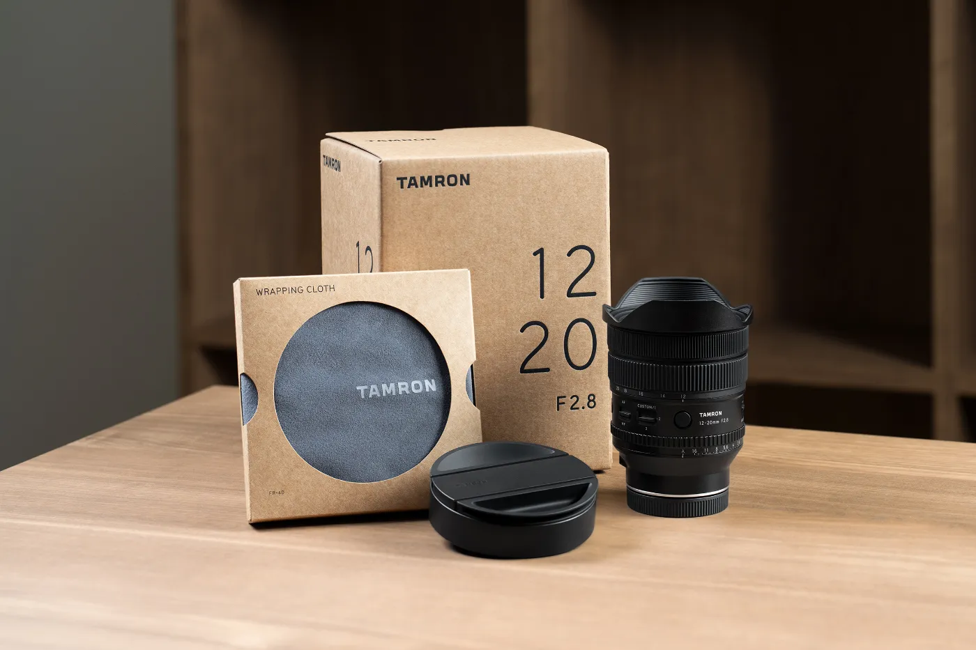 Tamron 12-20mm F2.8 met lensdop, doos en wikkeldoek op een houten tafel