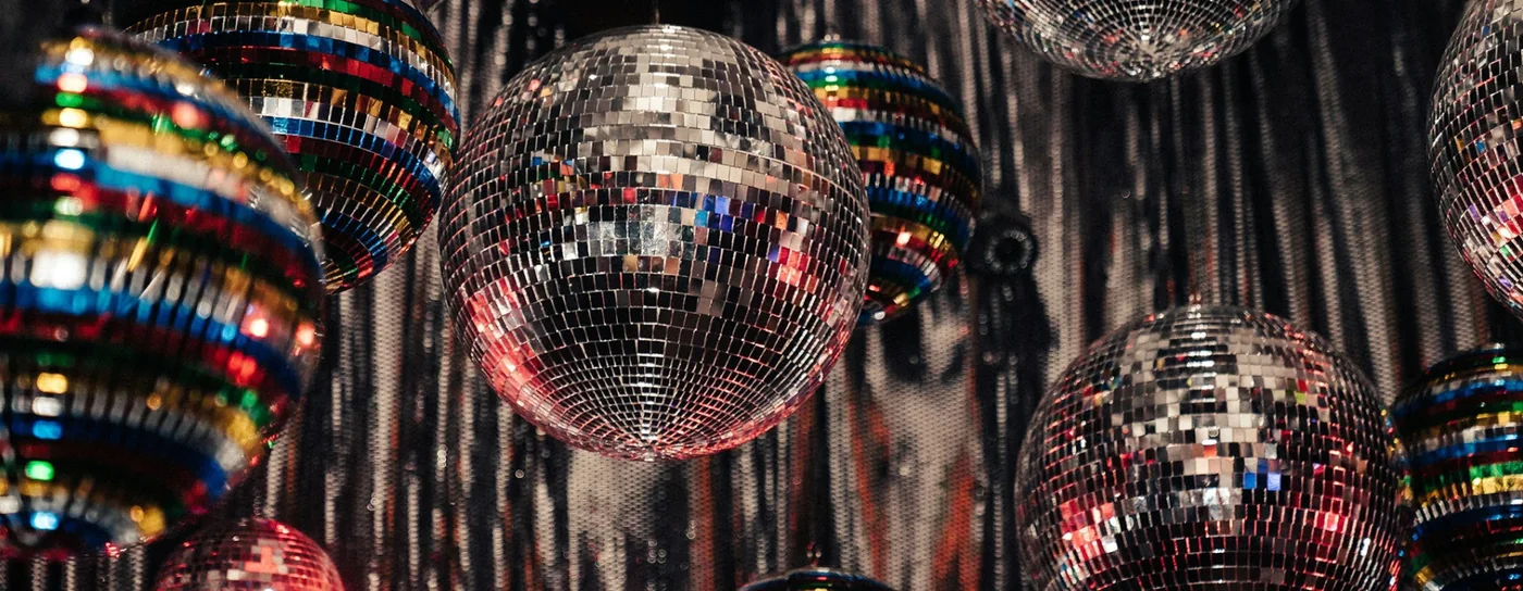 Discoballen en glinsterende achtergrond bij de tentoonstelling DISCO in Wereldmuseum Amsterdam.