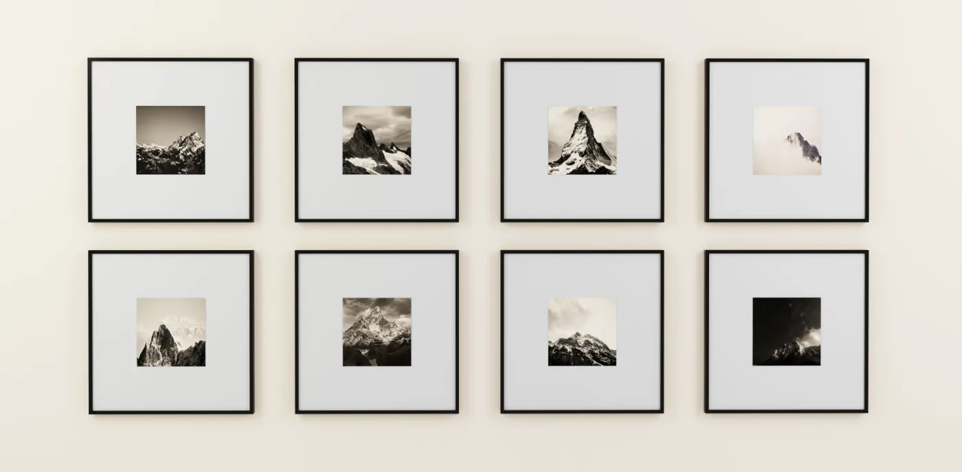 Acht ingelijste zwart-witfoto’s van bergen, netjes gerangschikt aan een lichte wand.