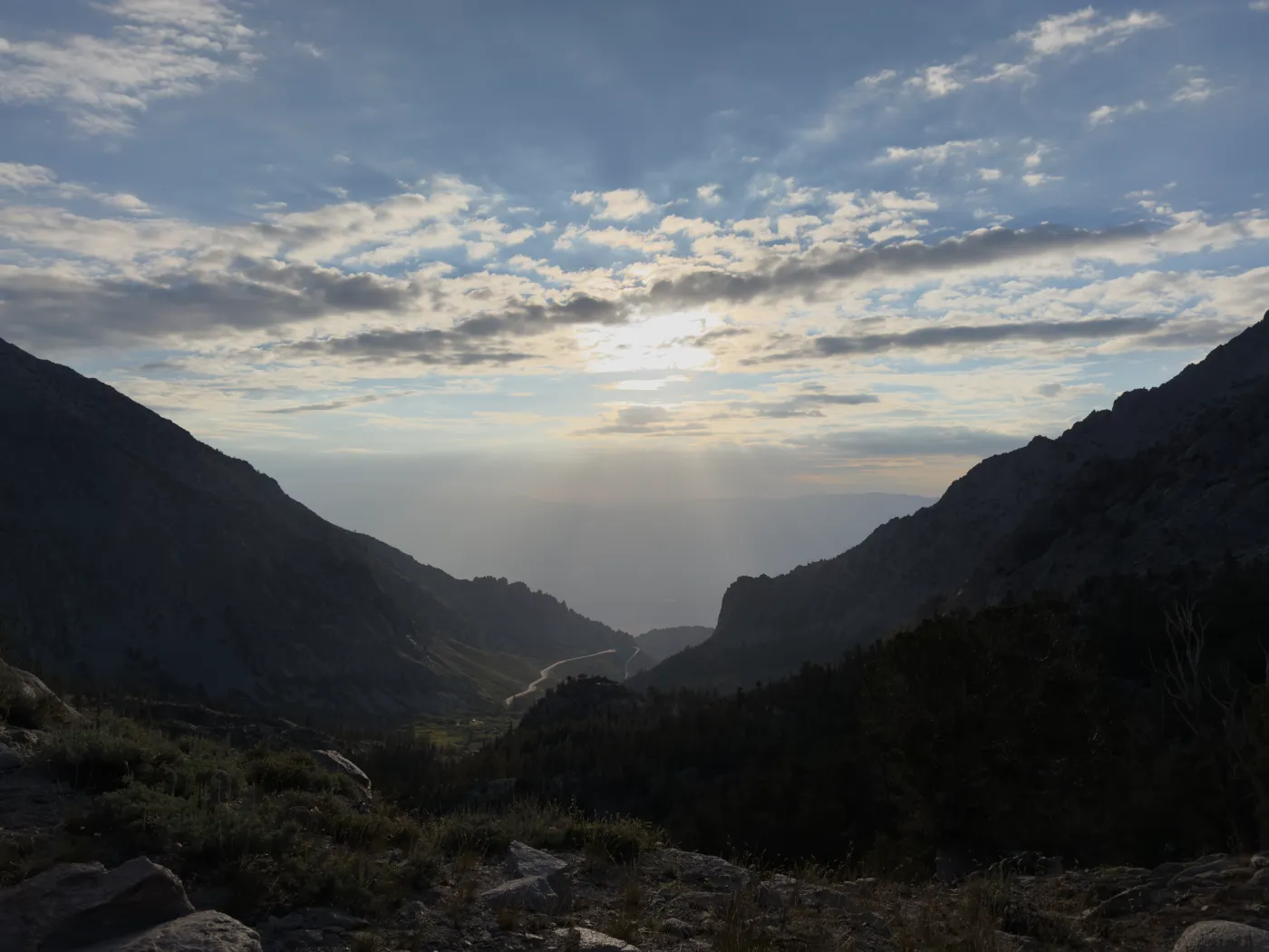 Donkere JPG-foto van een bergvallei bij Kearsarge Pass met zonlicht tussen de wolken.