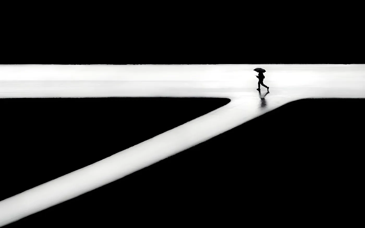 Figuur met paraplu op een helder kruispunt in een minimalistisch zwart-witbeeld