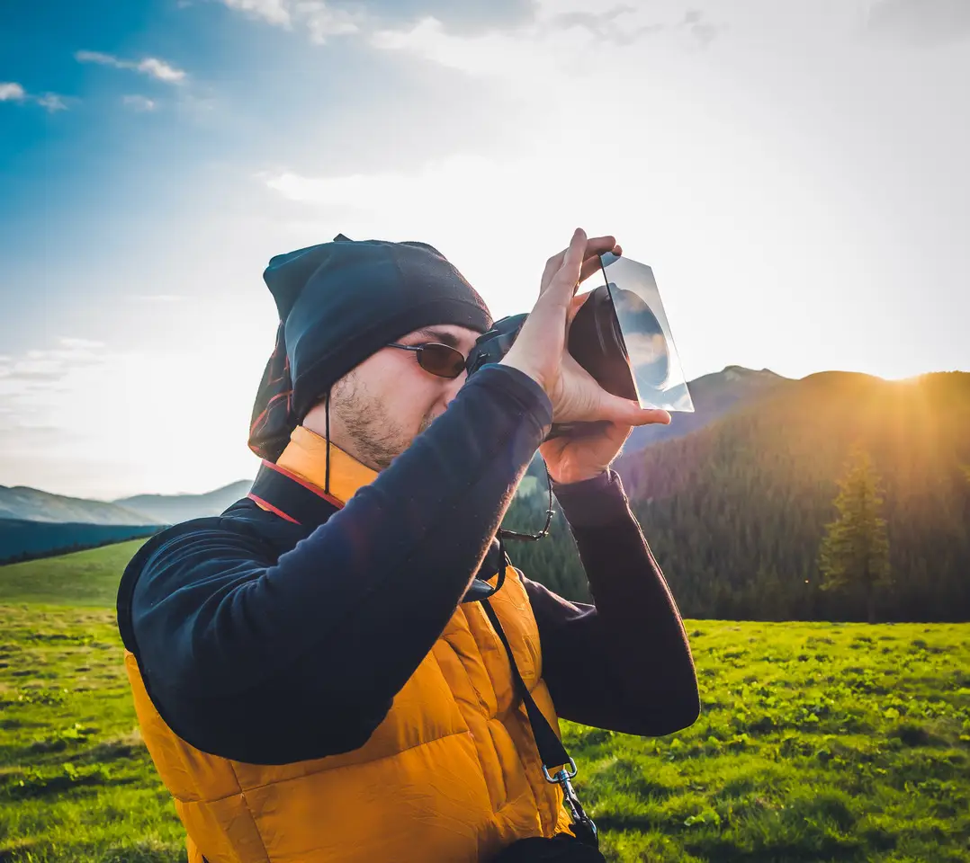 Photographer in a mountain landscape at sunset with a large difference between light and shadow