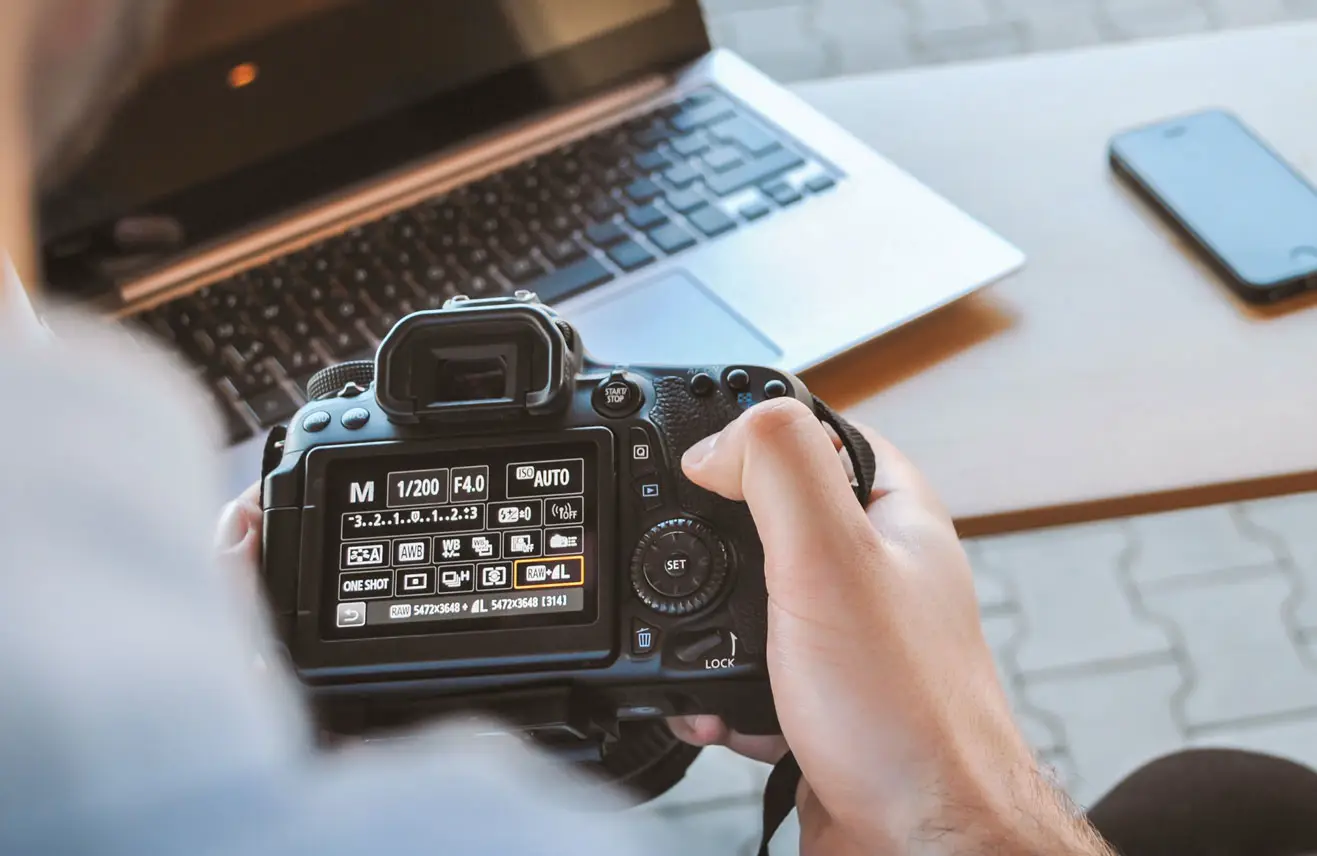 man stelt camera in bij laptop op bureau