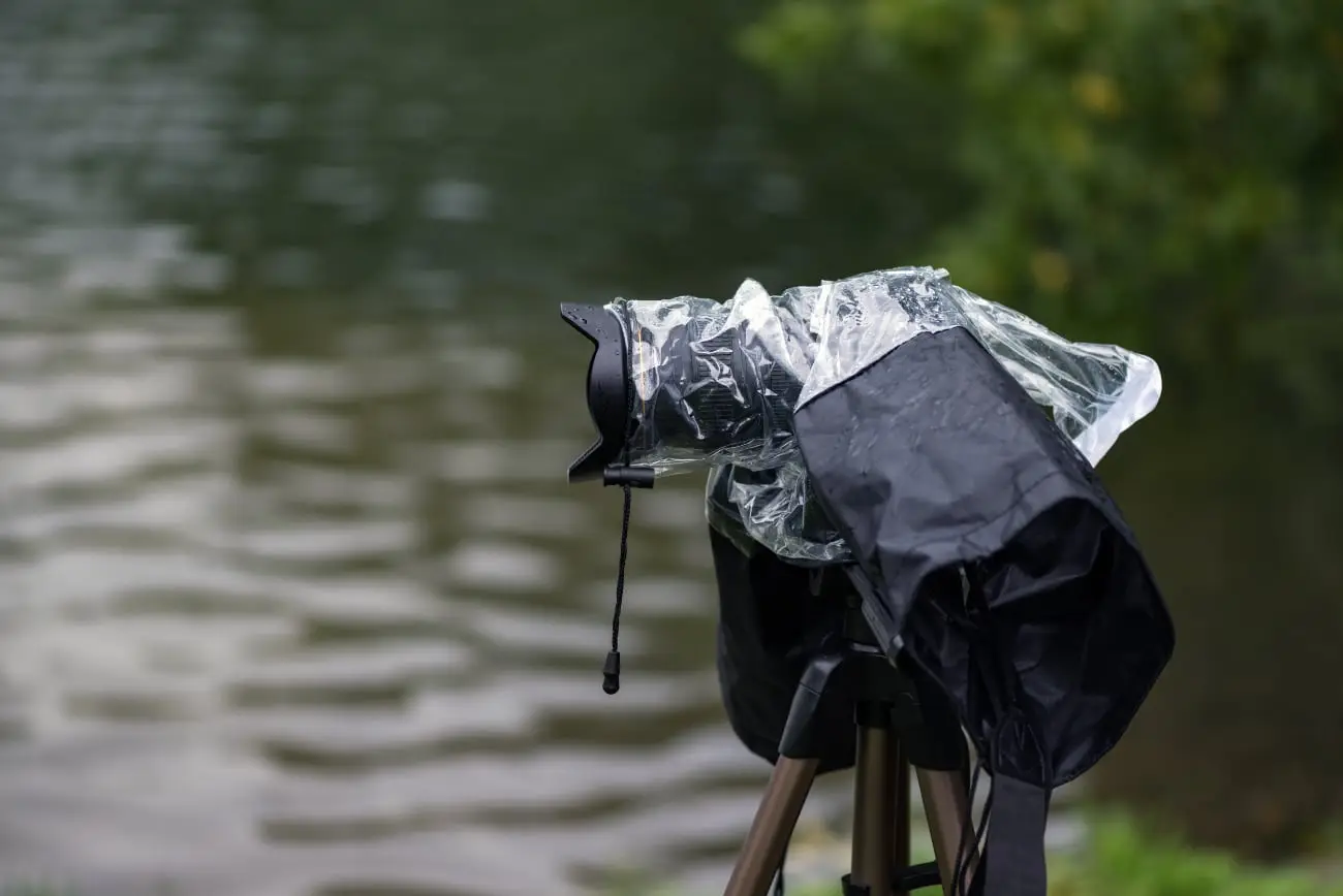 Camera op statief is beschermd met een regenhoes bij het fotograferen in nat weer.