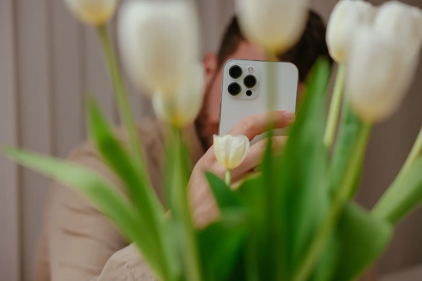 Persoon fotografeert witte tulpen van dichtbij met een ismartphone