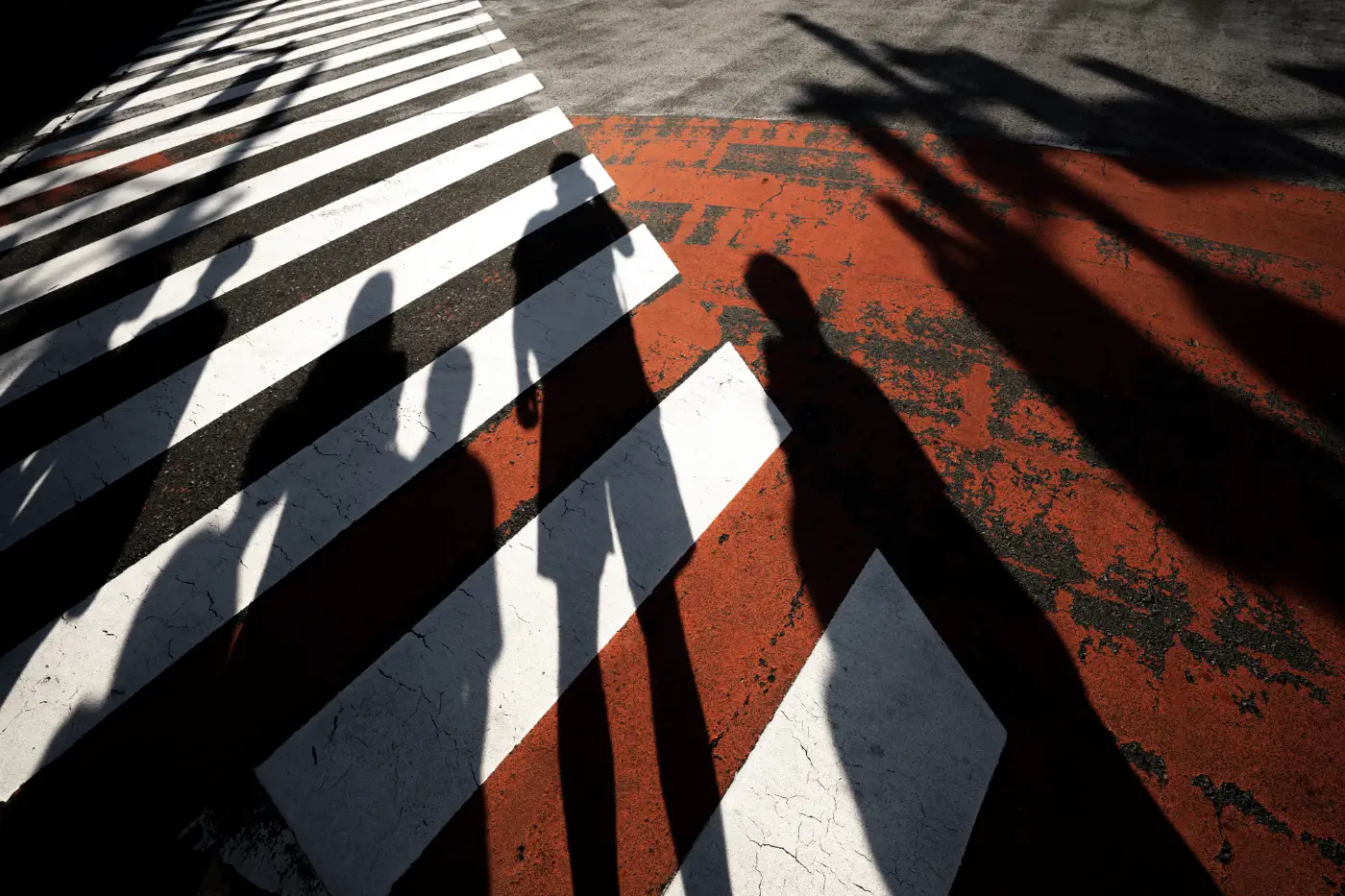 Silhouetten van mensen tussen rode en witte kleurvlakken in hard zonlicht