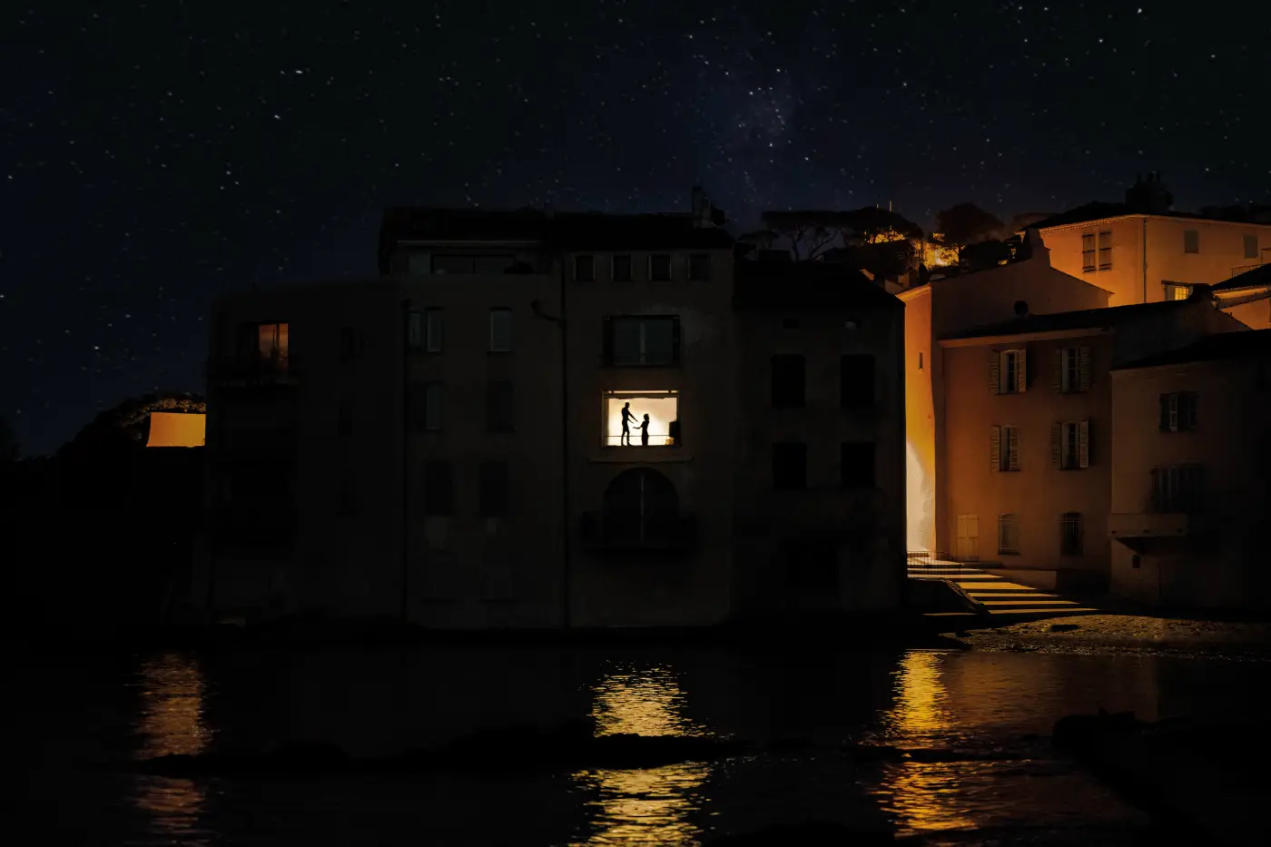 Twee silhouetten in een verlicht raam aan het water tijdens een sterrennacht in Saint-Tropez