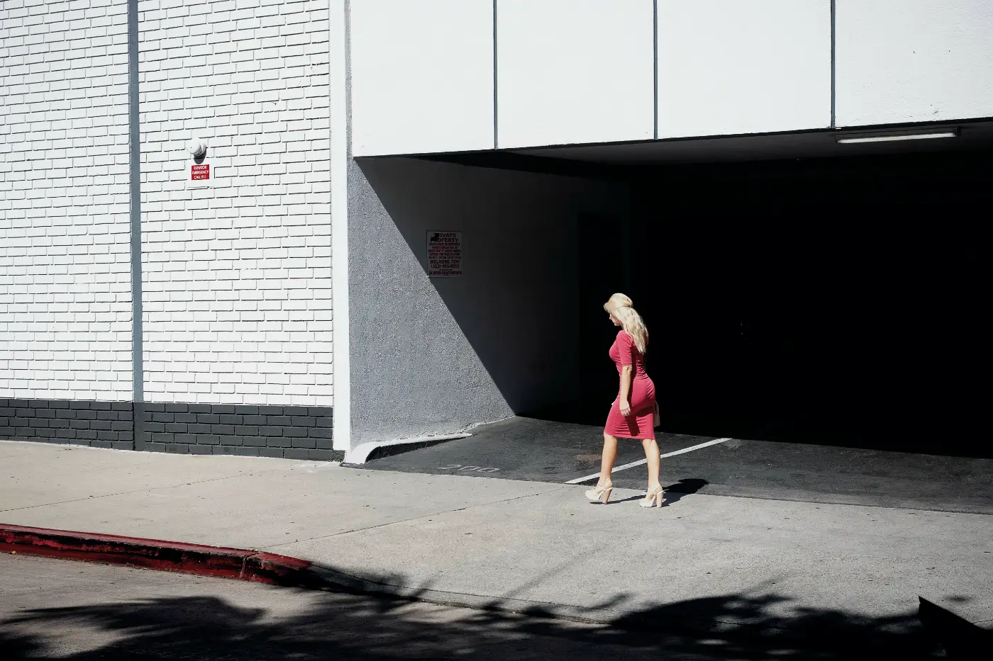 Vrouw in een roze jurk voor een donkere garageopening in Los Angeles