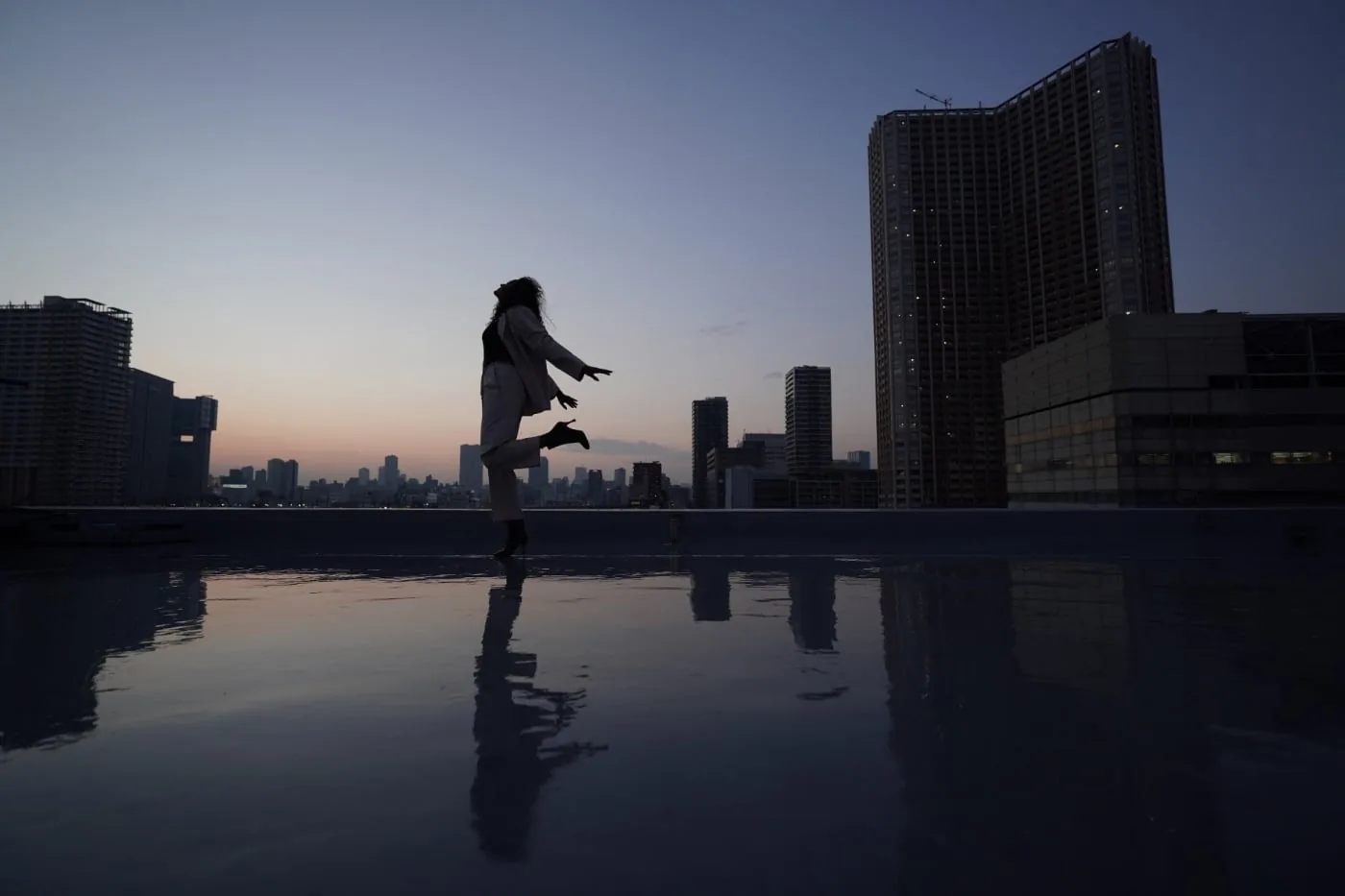 Woman jumps into a puddle on a roof, photographed with a Sony wide-angle lens