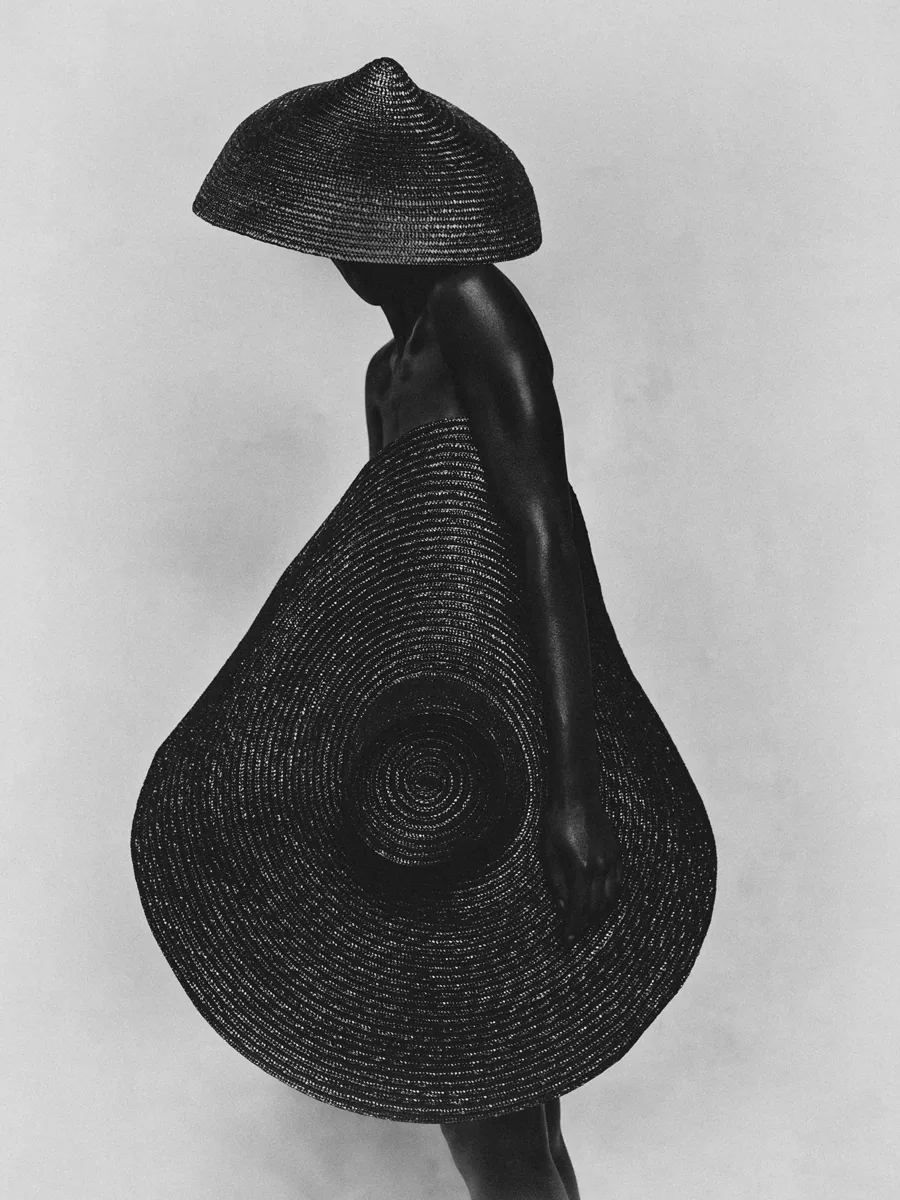 photo: © Rhythm - Bastiaan Woudt, black-and-white portrait of a figure wearing a wide woven hat and circular woven garment