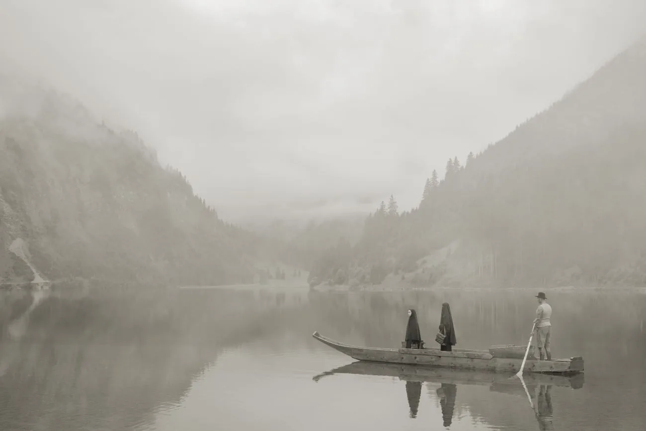 Foggy mountain lake with a boat and three people