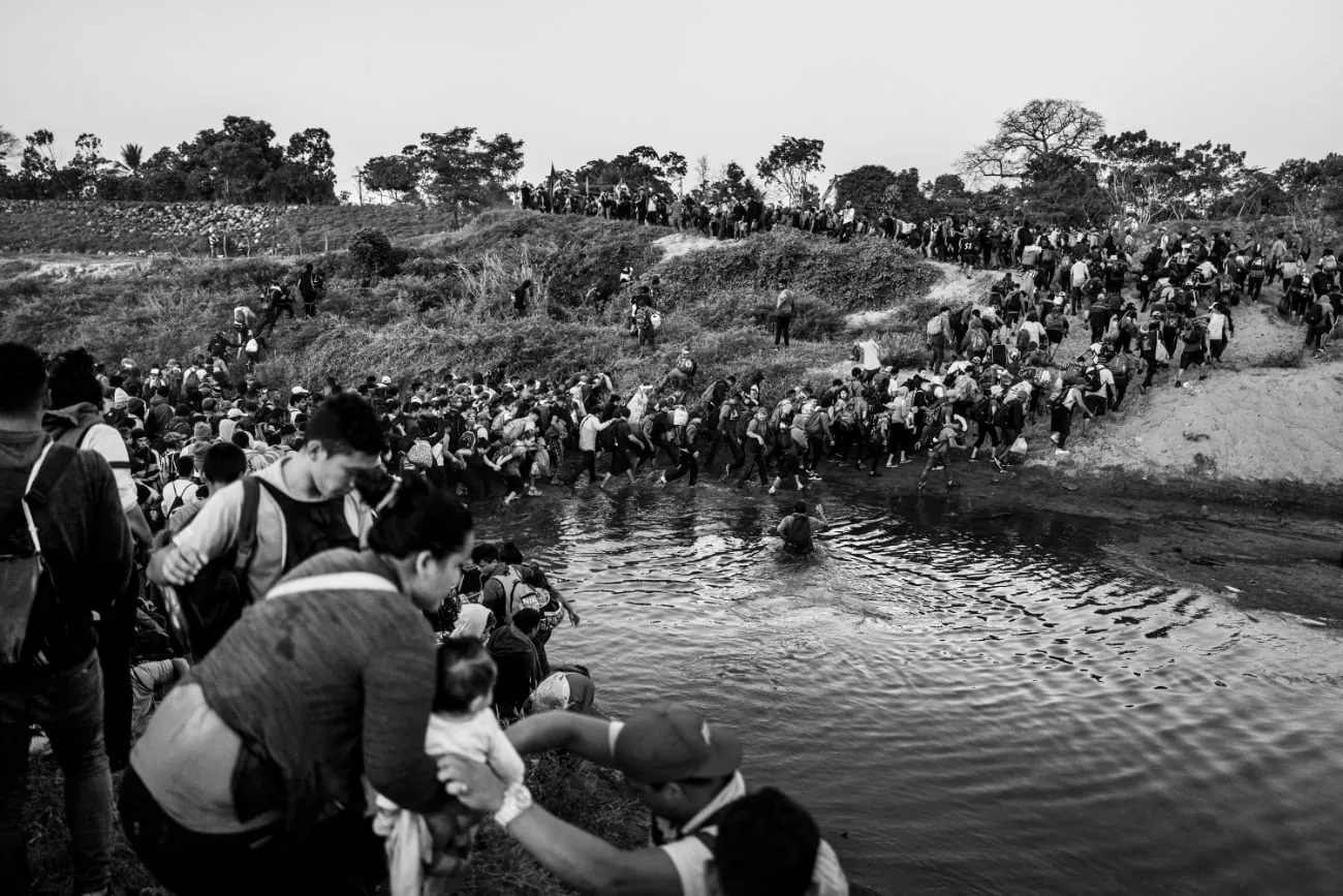 Groep migranten steekt een rivier over tijdens de tocht richting de Verenigde Staten