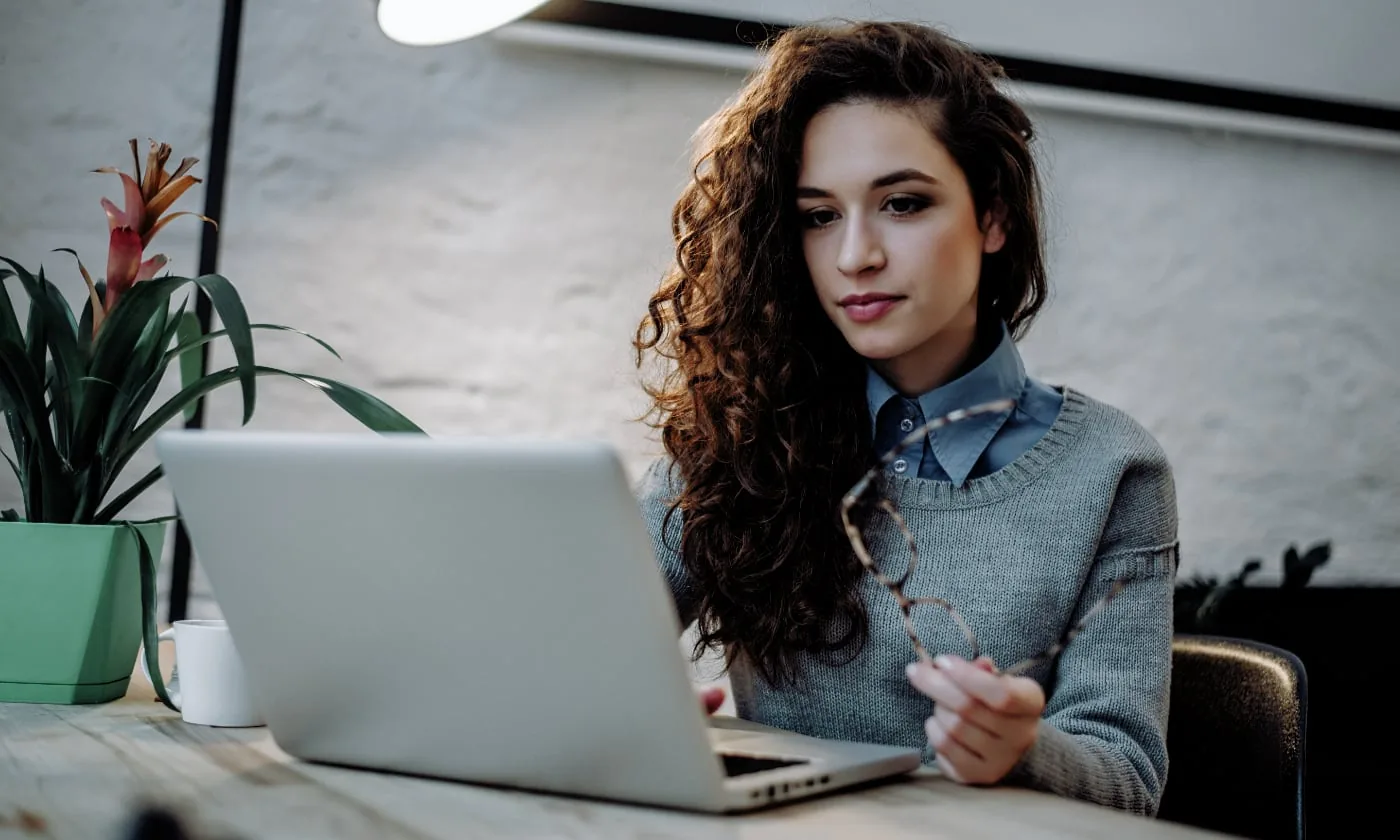 Woman works behind a laptop at a table