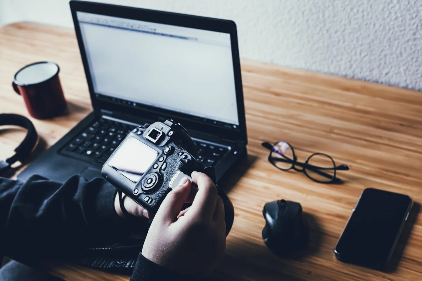 Photographer looks at a camera next to a laptop on a desk