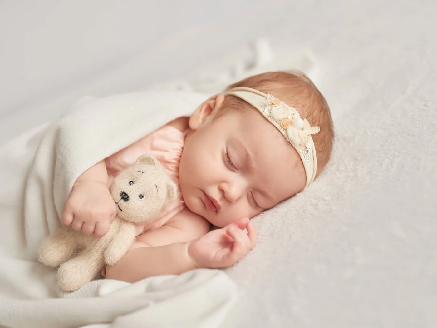 Sleeping baby with a teddy bear in soft natural light