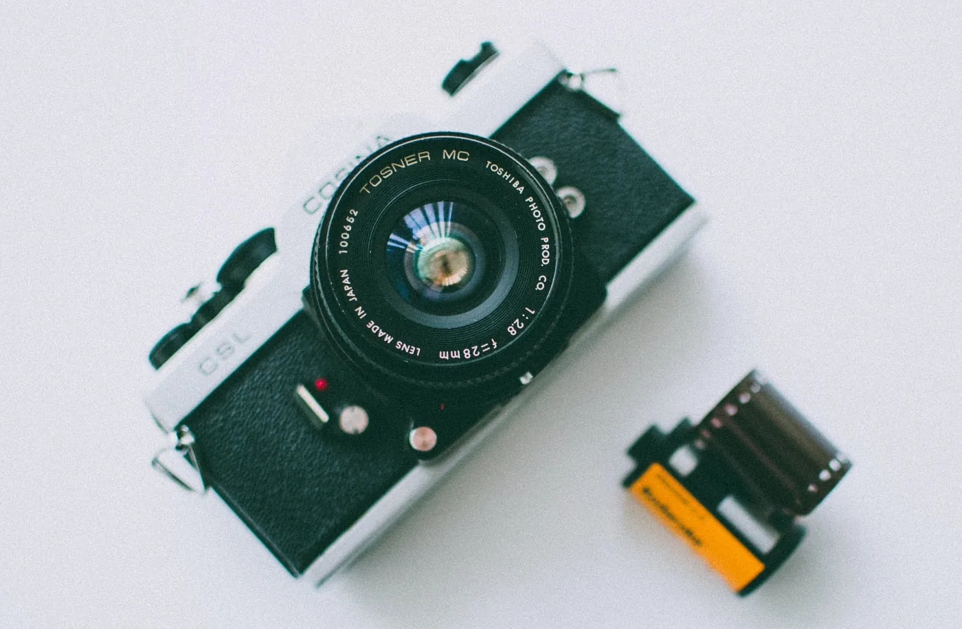 Analoge spiegelreflexcamera met een gedeeltelijk afgerold fotorolletje op een witte ondergrond