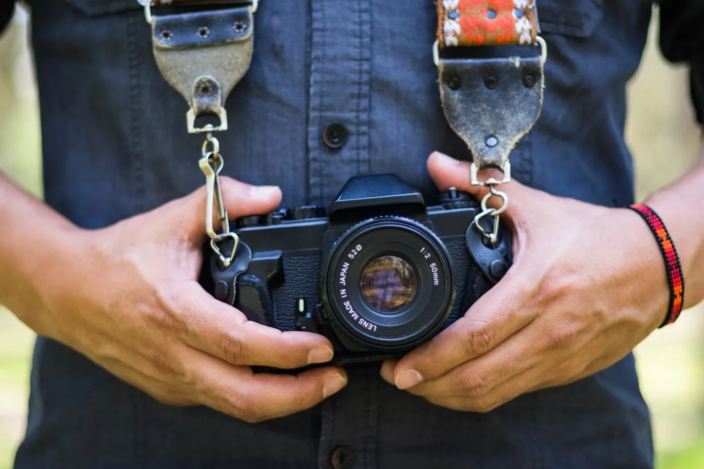 Fotograaf houdt een zwarte analoge spiegelreflexcamera met 50mm-objectief vast