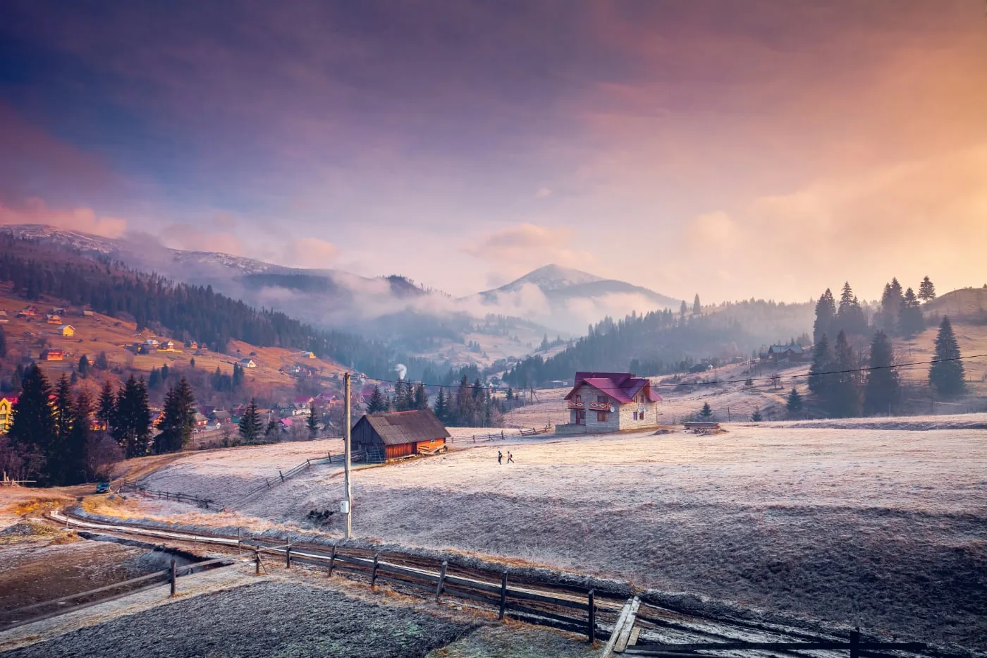 Mountain village in a winter landscape with pink morning light and mist between the mountains